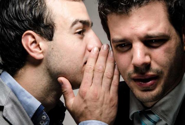 Businessman whispering into ear of another businessman