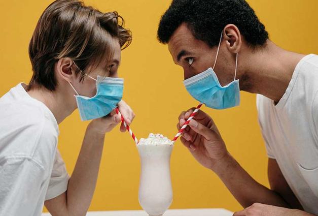 Young couple wearing face masks while sharing an ice cream sundae