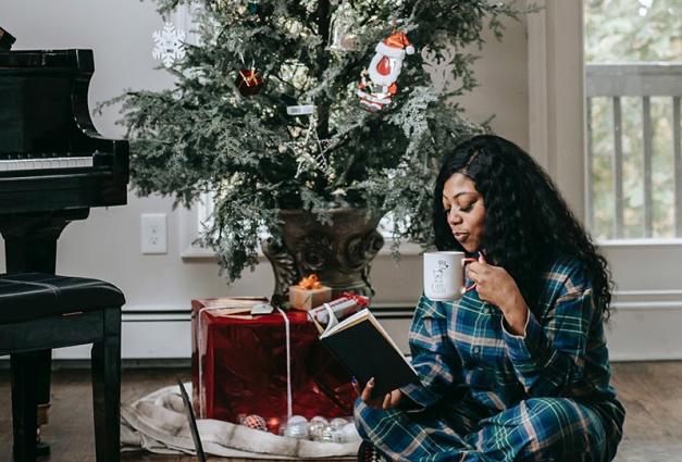 Calm black woman drinking coffee and reading book
