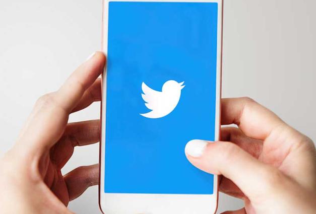Hands holding mobile phonr with Twitter logo on screen