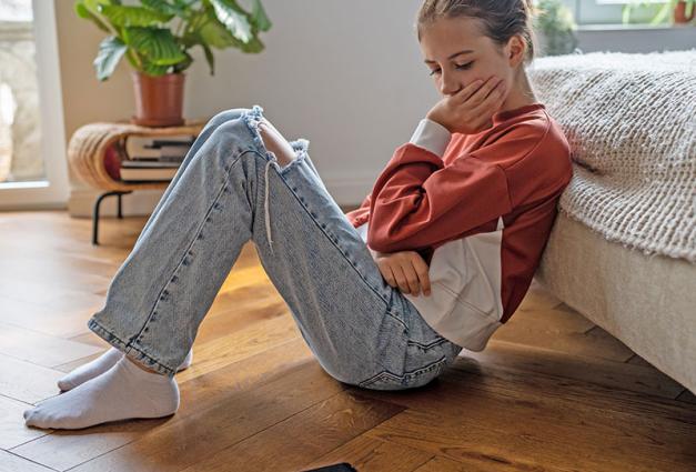 Young woman sitting on floor looking at cell phone