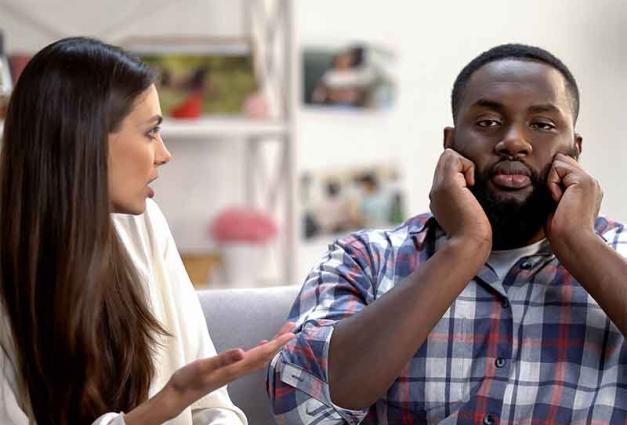 Woman speaking to man who is plugging his ears with his fingers