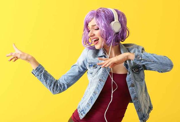 Young woman wearing headphones and dancing
