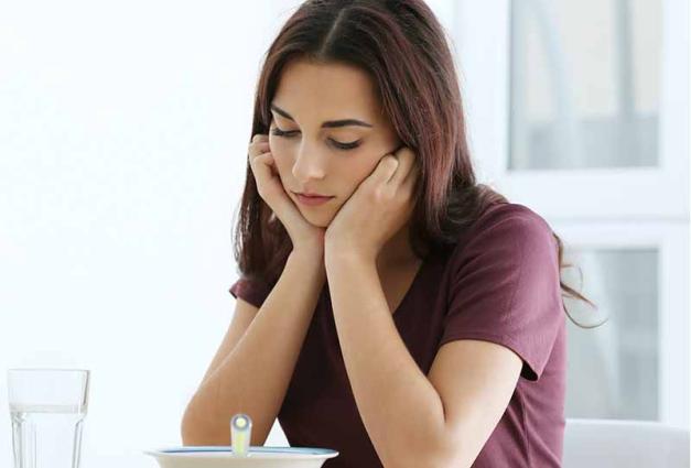 Depressed woman sitting at kitchen table