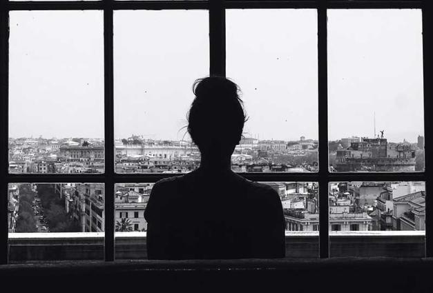 Woman standing in front of glass window looking at city