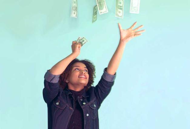 Woman reaching for money falling from above
