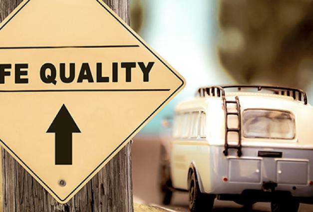 Image of a camper driving in direction of a sign that read Life Quality ahead