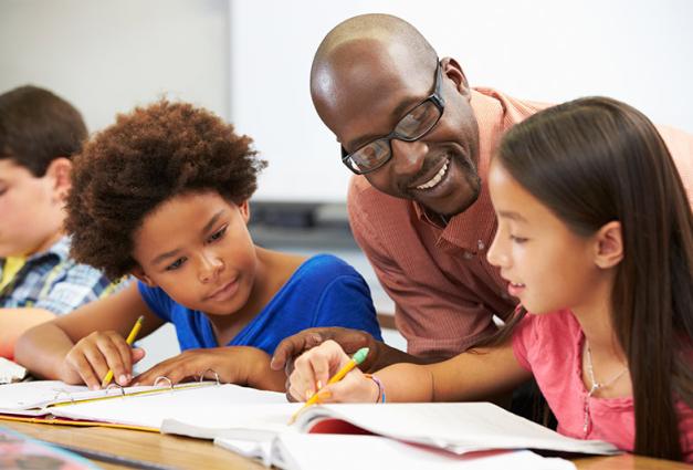 Image of teacher working with young students on schoolwork