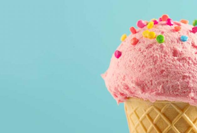 A scoop of pik ice cream, maybe strawberry flavored, sits atop a suagr cone and is topped with raninbow colored sprinkles. The ice cream and cone are against a candy blue background