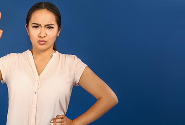 angry Asian woman with raised index finger on color background