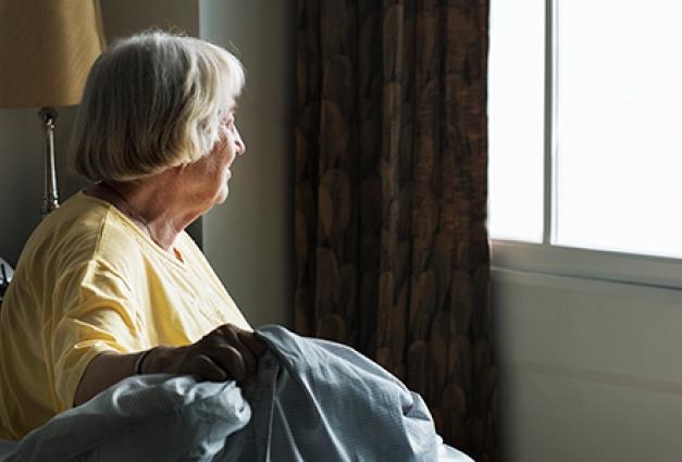 Senior woman sitting in bed alone looking out window