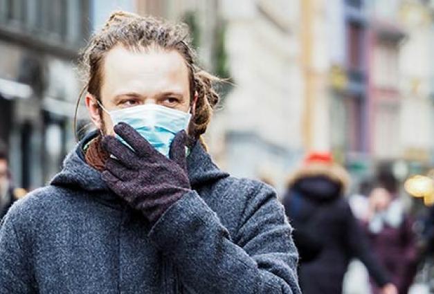 young European man on the street with a medical face mask on. 