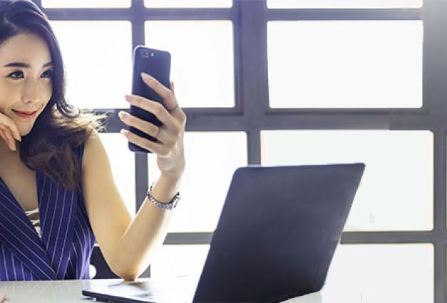 Young asian business woman holding smartphone taking selfie