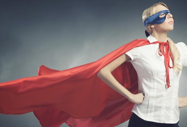Image of empowered woman with a cape and mask on looking off into the distance with her hands on her hips.