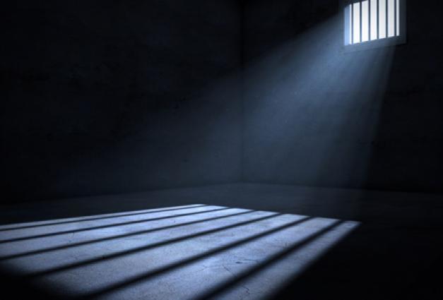 Image of light entering an empty dark jail cell
