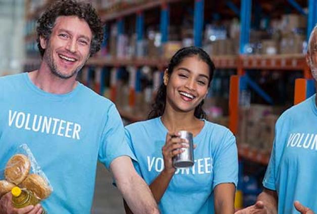 Happy volunteers are posing and smiling during their volunteer work in a warehouse