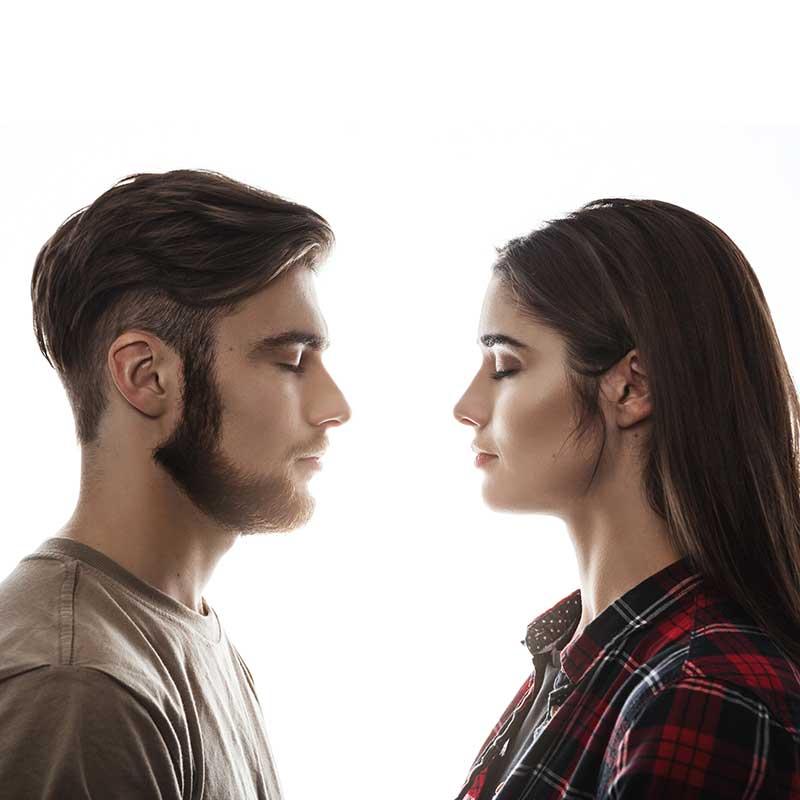 Young man and woman facing one another with their eyes closed