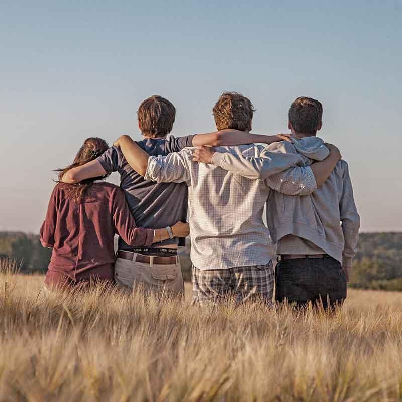 Four adults embracing in a field