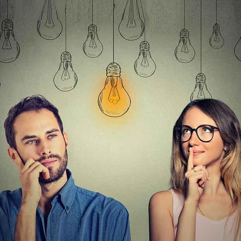 Man and woman with inquisitive expressions and a lit lightbulb between their heads 