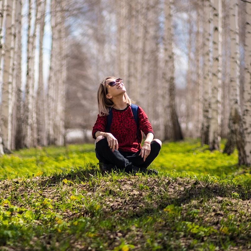 Woman sitting on the ground in a wooded area