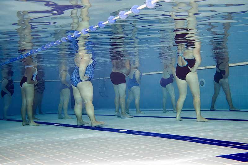 underwater view of ladies aerobics class in a pool, with various body sizes and ages