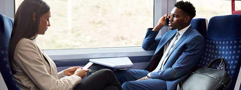 Business Passengers Sitting In Train Commuting To Work Using Mobile Phone