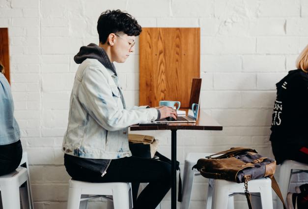 image of young man sitting at cafe table working on laptop