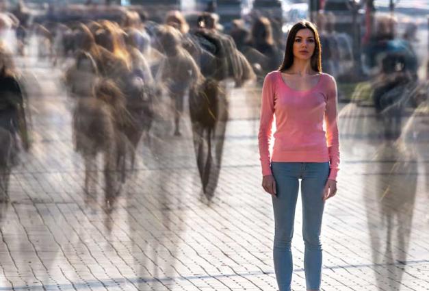 Young woman standing on street surrounded by ghostly figures