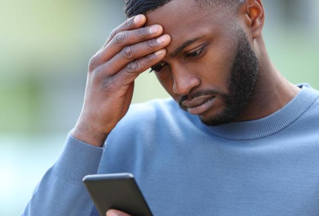 Worried Black man checking phone