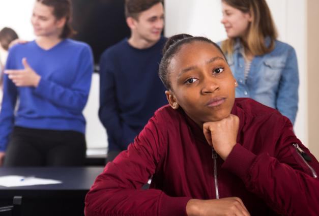 Black teen sitting in front of White classmates