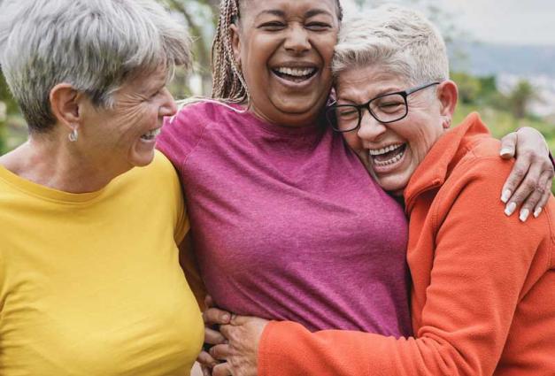 Three multiracial senior women hugging each other outdoors