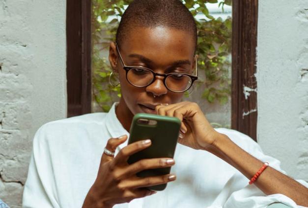 Young woman looking at mobile phone screen looking upset