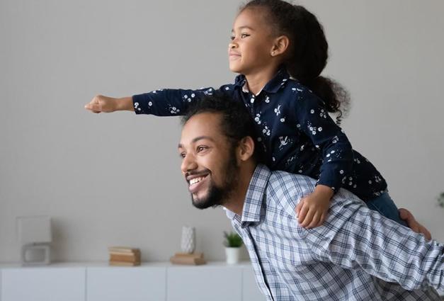 young black girl with fist in the air on the back of her father