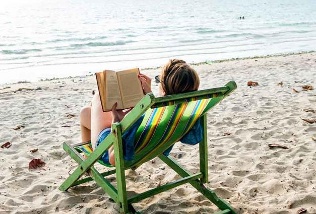 Woman sitting on beach reading a book