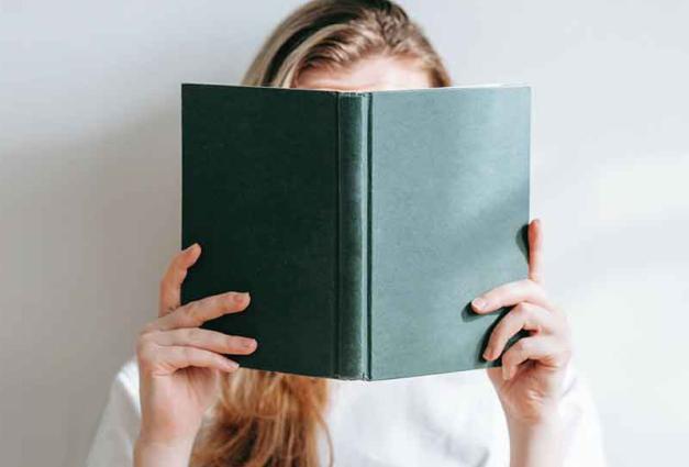 Woman holding a book in front of her face