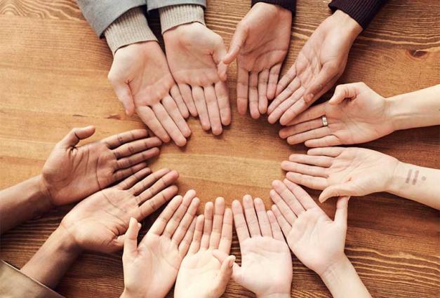 Group of people in circle with hands face up touching each other 