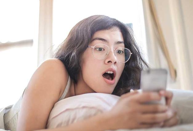 Young woman with shocked expression looking at mobile device