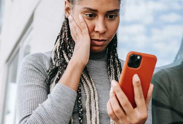 Woman with concerned expression looking at her mobile phone