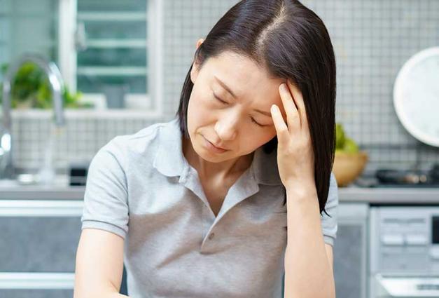 Discouraged woman sitting at kitchen table with head in her hand