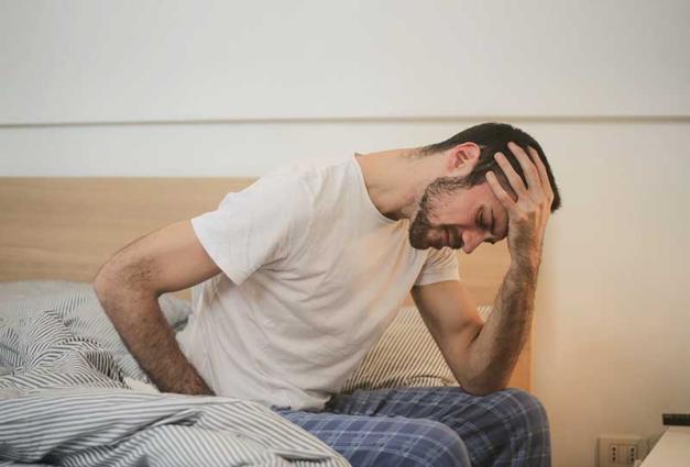 Man sitting in bed experiencing pain