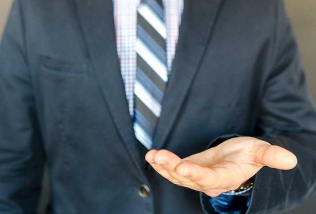 Man wearing a suit with a hand outreached, palm up