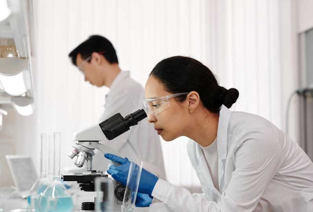 Woman in lab using a microscope