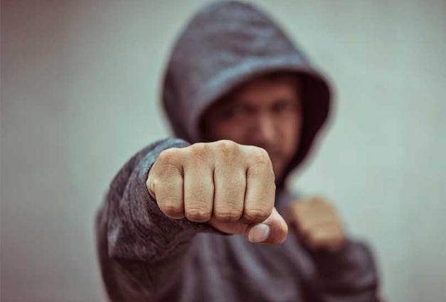 Man in hoodie with fist aimed at camea