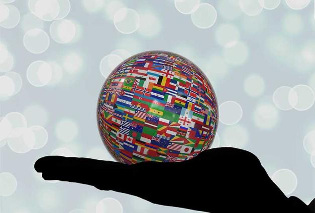 Silhouette of a hand holding an orb constructed of flags from different countries multicolored people