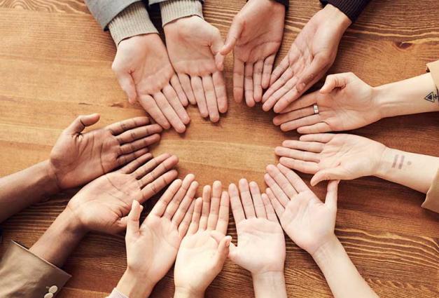 People's hands touching and forming a circle on a table