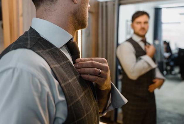 Well dressed Man looking in a mirror and fixing his tie