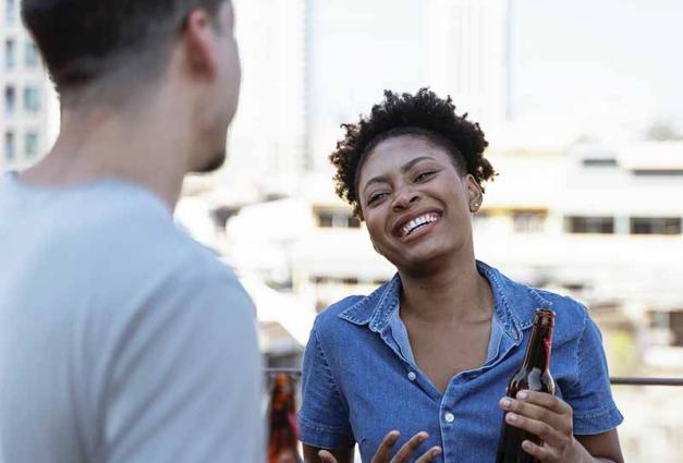  smiling and laughing Woman holding a beer bottle and talking to a man