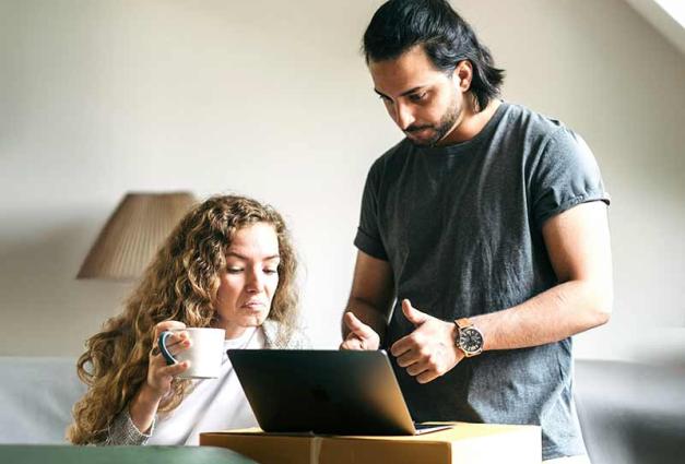 Couple looking at computer screen; man is giving a thumbs up