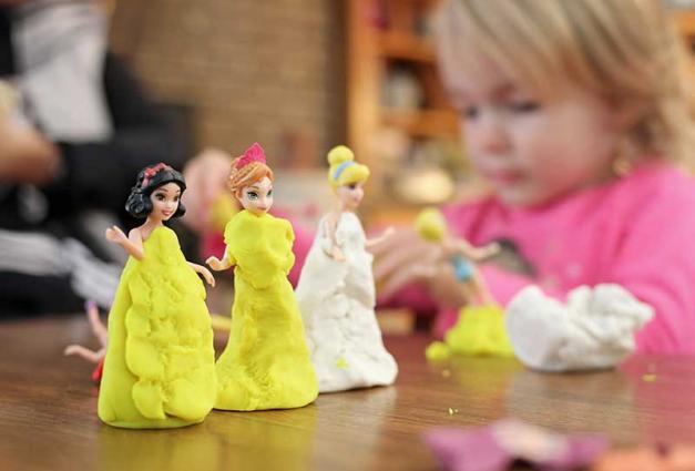 Young child playing with Princess dolls