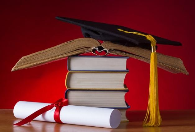 Image of a diploma and a graduation cap on top of a stack of books